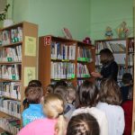 Uczestnicy lekcji bibliotecznej: bibliotekarka oprowadza po bibliotece