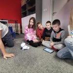 Klub Młodego Programisty. Uczestnicy siedzą przed robotem PhotonEdu , który sterują za pomocą tabletu