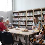 Spotkanie w bibliotece. bibliotekarka trzyma książkę